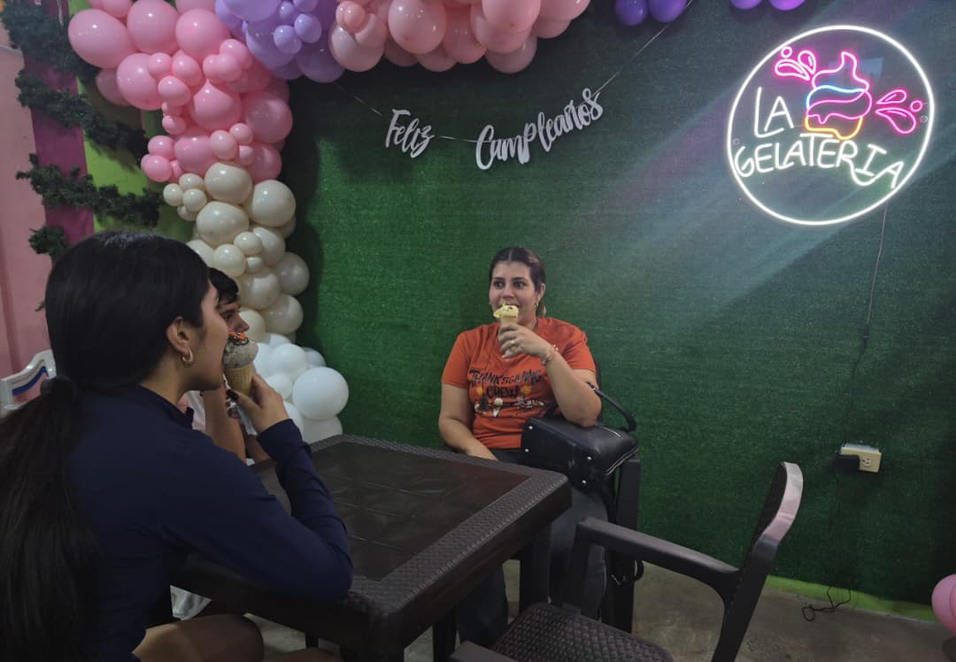 Familia y clientes disfrutando helado bajo el letrero de La Gelateria
